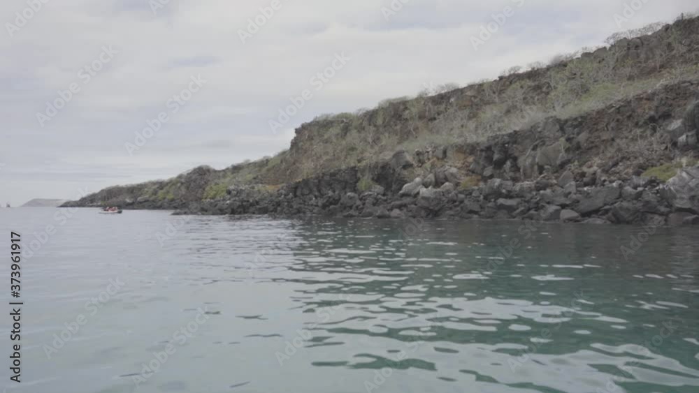 A large island filled with green plants and volcanic rocks and small hills. The place is part of the Galapagos islands. A large island filled with green plants and volcanic rocks and small hills. The place is part of the Galapagos islands.