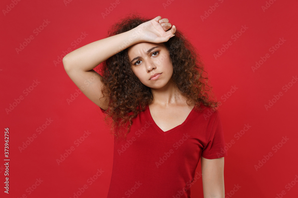 Exhausted tired young african american woman girl in casual t-shirt posing isolated on red wall background studio portrait. People emotions lifestyle concept. Mock up copy space. Put hand on head. Exhausted tired young african american woman girl in casual t-shirt posing isolated on red wall background studio portrait. People emotions lifestyle concept. Mock up copy space. Put hand on head.