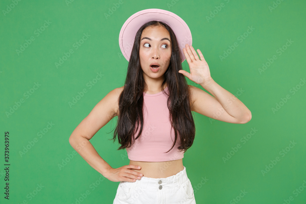 Amazed young asian woman girl in casual pink clothes hat posing isolated on green background studio portrait. People lifestyle concept. Mock up copy space. Try to hear you overhear listening intently. Amazed young asian woman girl in casual pink clothes hat posing isolated on green background studio portrait. People lifestyle concept. Mock up copy space. Try to hear you overhear listening intently.
