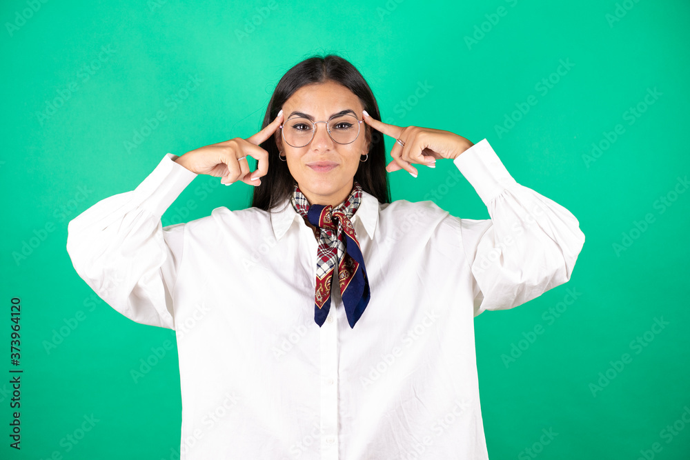 Young beautiful business woman over isolated green background smiling and thinking with her fingers on her head that she has an idea. Young beautiful business woman over isolated green background smiling and thinking with her fingers on her head that she has an idea.