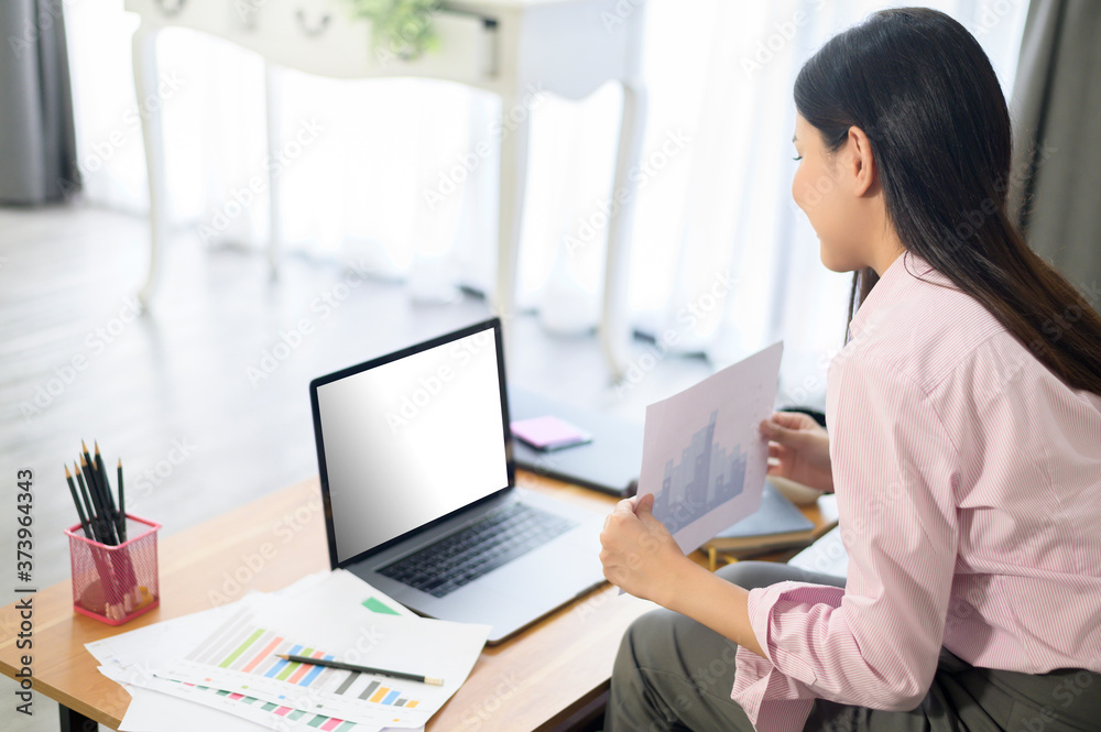 A business woman is working with laptop mock up screen, analyzing business plan in home office. A business woman is working with laptop mock up screen, analyzing business plan in home office.