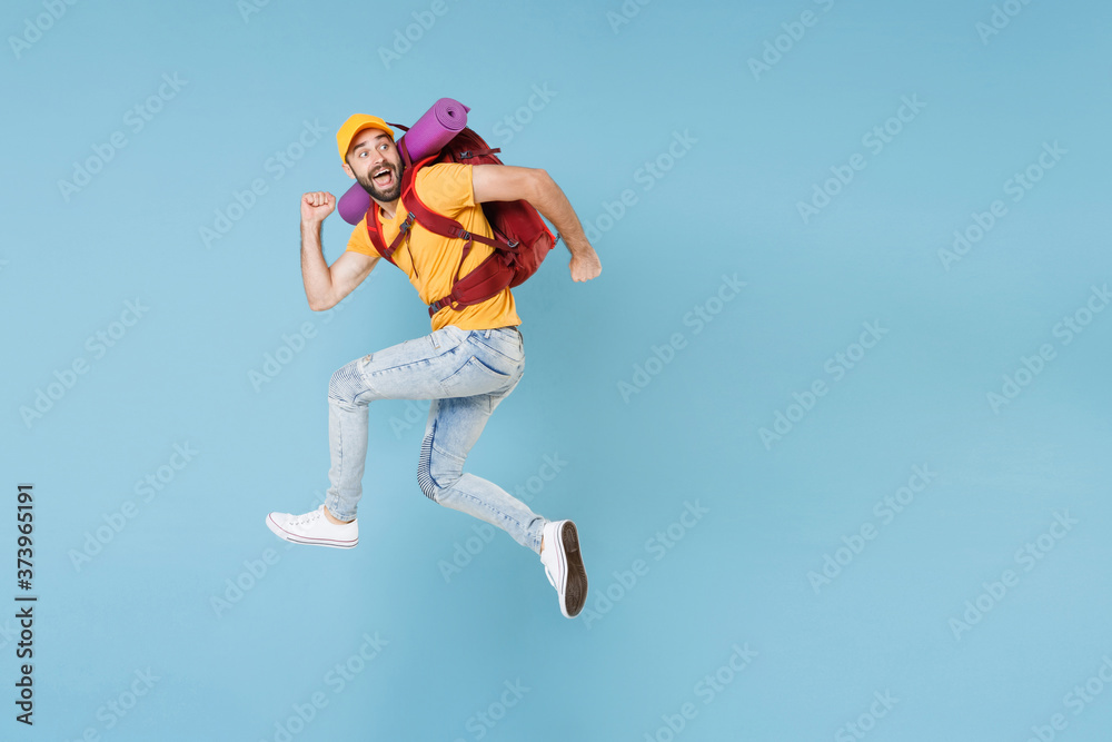 Full length portrait Amazed young traveler man in t-shirt cap with backpack isolated on blue background. Tourist traveling on weekend getaway. Tourism discovering hiking concept. Jumping like running. Full length portrait Amazed young traveler man in t-shirt cap with backpack isolated on blue background. Tourist traveling on weekend getaway. Tourism discovering hiking concept. Jumping like running.