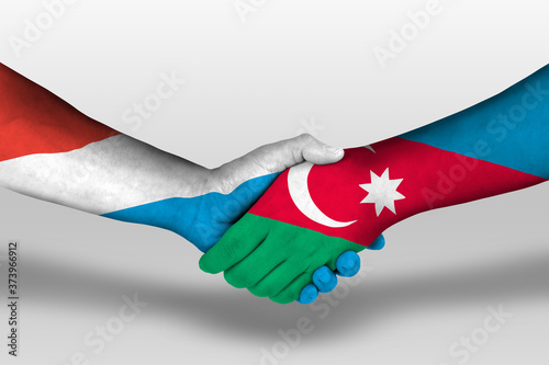 Handshake between azerbaijan and luxembourg flags painted on hands, illustration with clipping path.
