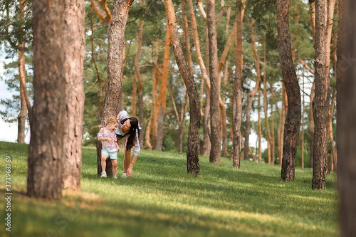 Mom and daughter are running in the forest close-up and copy space. The sisters are playing hide and seek in the forest. Mother's day, women's holiday.