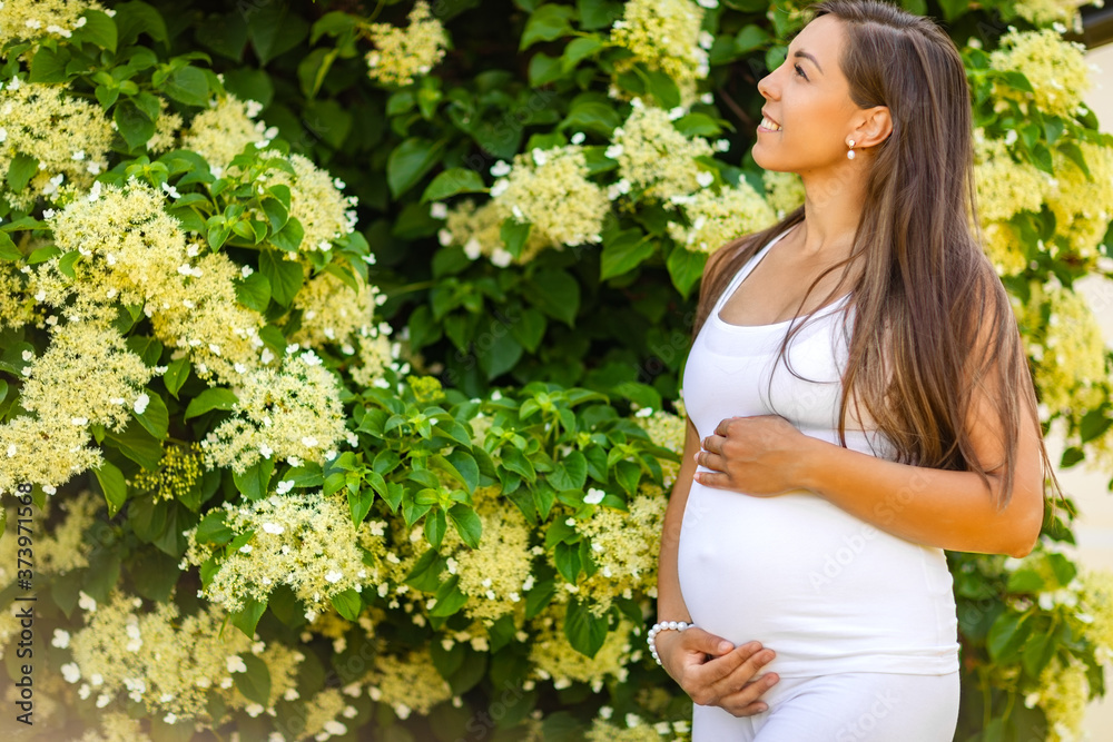 Dreamy smiling pregnant woman in beautiful garden looking at the sky Dreamy smiling pregnant woman in beautiful garden looking at the sky
