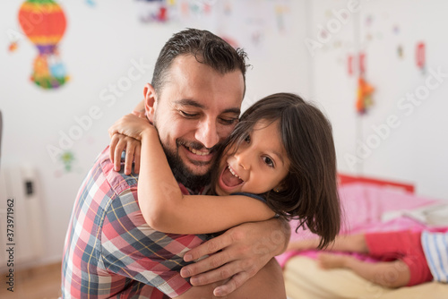 Father embraces his daughter with much love in the family bedroom photo