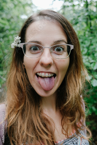 portrait of a young woman with glasses and prosthesis making funny faces