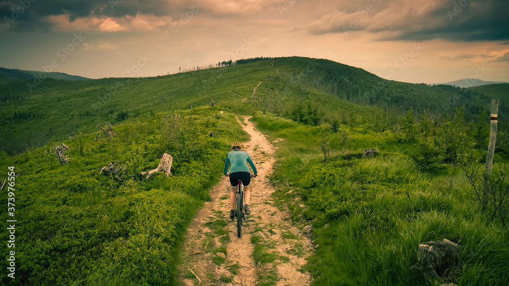 Cycling woman riding on bike in autumn mountains forest landscape. Woman cycling MTB flow trail track. Outdoor sport activity.