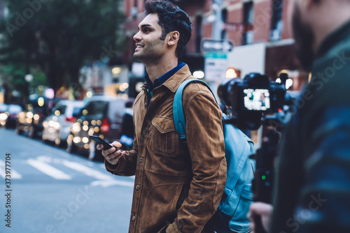 Happy man walking with smartphone in hand at street