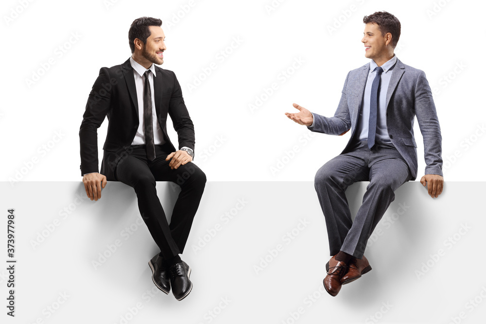 Male colleagues sitting on a blank panel and having a conversation Male colleagues sitting on a blank panel and having a conversation