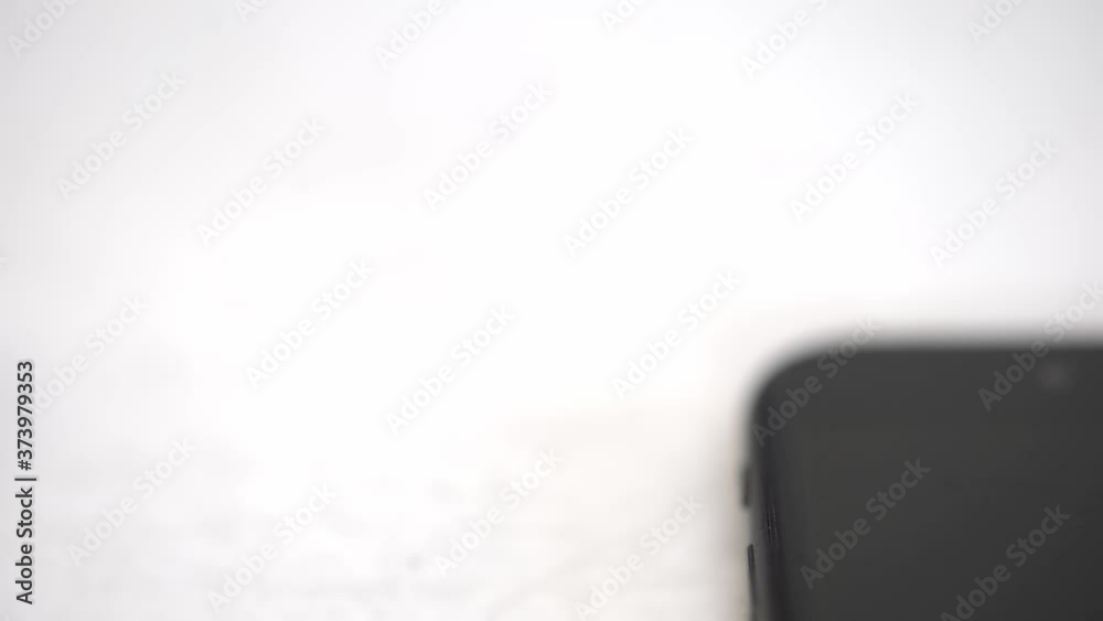 Overhead shot of switching off the smartphone mobile phone swiping a button on a white desk. Closeup.