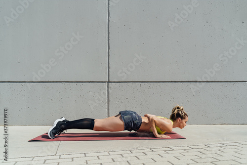 Bilde på lerret Woman doing yoga plank pose to strengthen back and abs on grey background