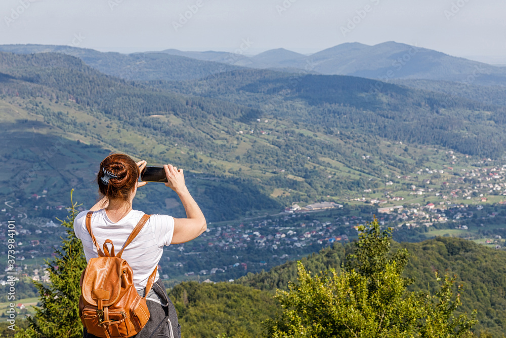 Tourist photographs on the phone a view of the mountainous area.