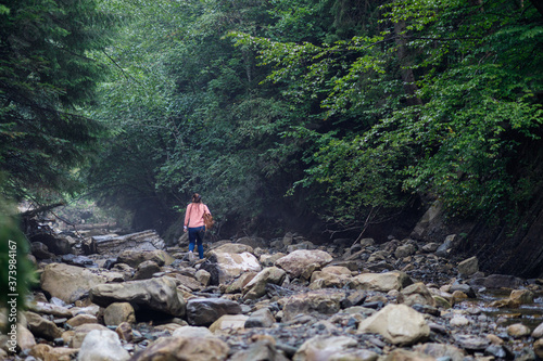 Tourist walks along the stones along the mountain river.
