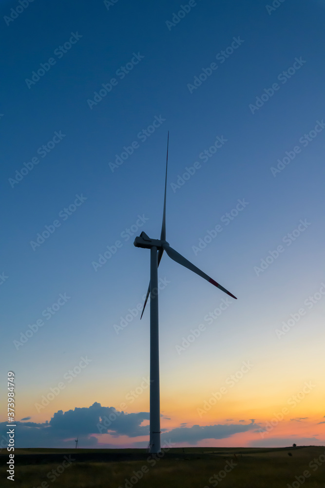 View of silhouette of wind turbine in wind farm in Russia at sunset. Renewable electricity generation theme.