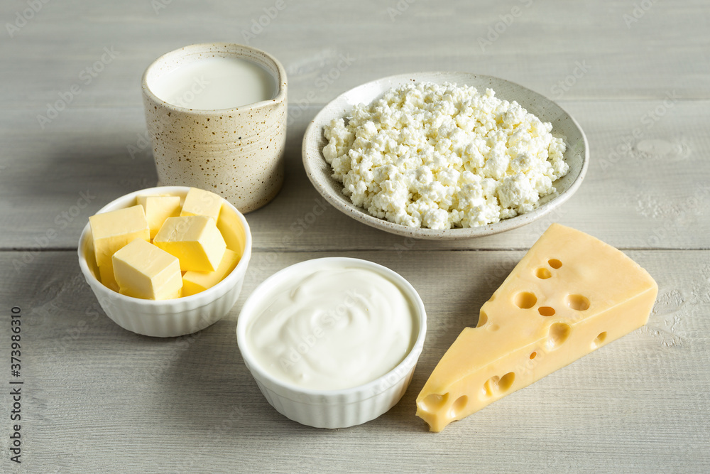 Most common dairy products are butter, cheese, milk, sour cream, cottage cheese in white dish on a white wooden background close up. Natural, organic food. Most common dairy products are butter, cheese, milk, sour cream, cottage cheese in white dish on a white wooden background close up. Natural, organic food.