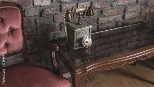 Elegant vintage old telephone on elegant wooden table against brick wall relaxing antique interior vintage decoration photo