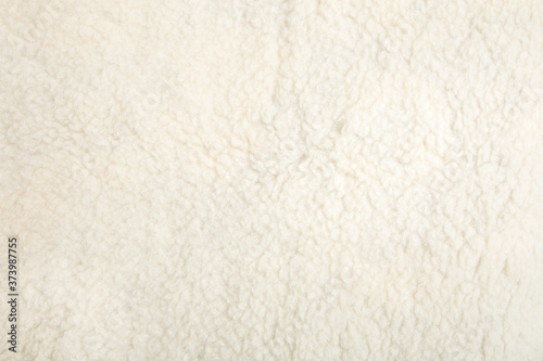 Top view of white soft sheepskin textile plaid. Warm cozy background.