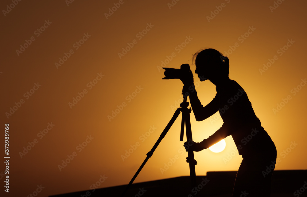 photographer taking pictures at sunset with dslr camera 
