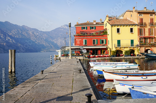 Sunny day in colorful marina of Malcesine with small boats tied up to the pier