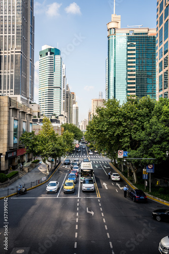 Perspectiva de calle en gran ciudad con tráfico y árboles y rascacielos al fondo generando un punto de fuga.