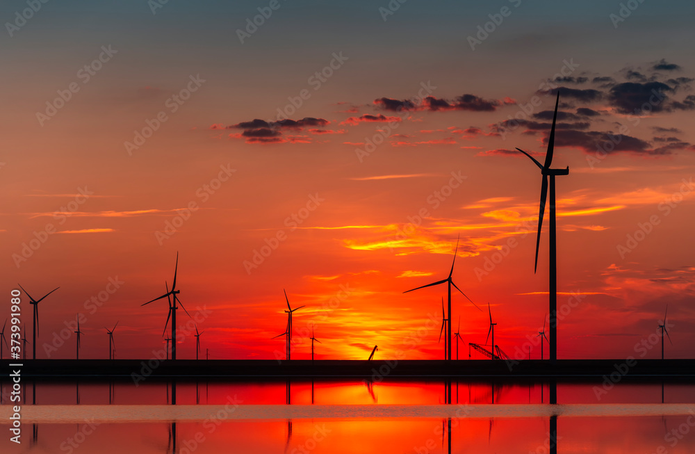 Wind farm at the sunset; wind turbines on the burning sky; background of wind farm