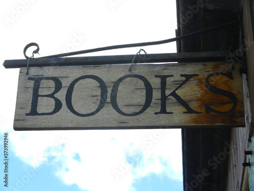 Old Bookstore Sign hanging from wall with blue cloudy sky at the