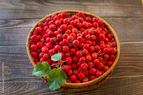 Red berries of hawthorn in the basket standing on a wooden table. Copy space.
