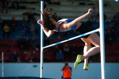 Obraz na plátně Woman jumping over bar at athletics meeting