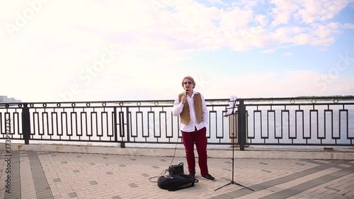 portrait of a young man who sings a song from the outside, a professional singer opens his mouth to music in the daytime on the street, hand of person holding a microphone