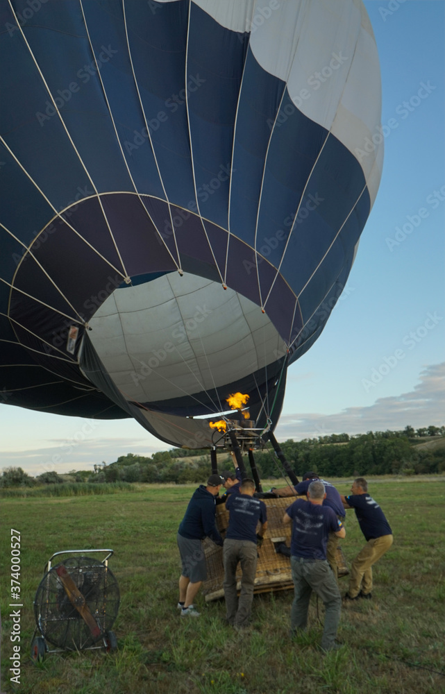 Obraz premium Inflating a balloon lying on the grass with burning air. A fire burning inside the ball 