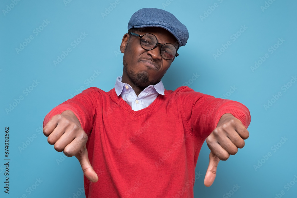 African man giving thumbs down gesture, looking with negative facial expression African man giving thumbs down gesture, looking with negative facial expression