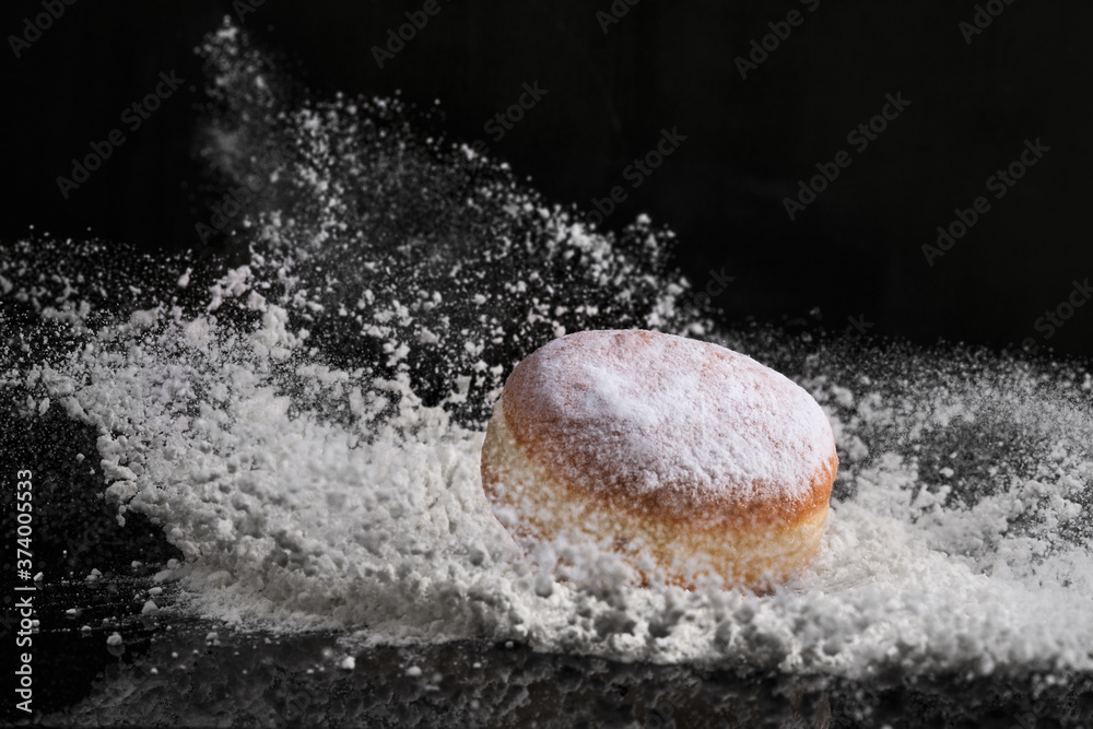 Berliner donut with jam stuffed falls into flour.