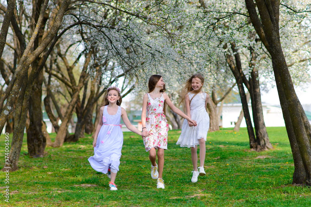 Three beautiful girls in retro dresses for a walk in a flowered garden. The idea and concept of a friendly family and a happy childhood.