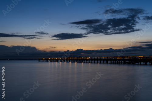 Long wooden jetty over sea during summer sunset with reflection in the water. Captured in south Sweden. © PhotosbyPatrick