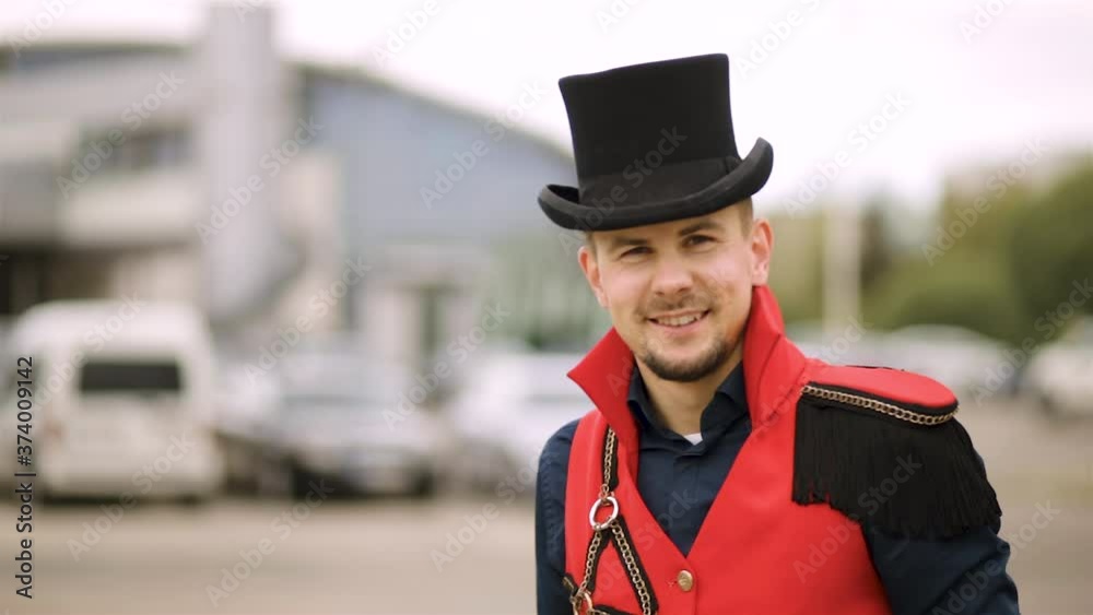 Male magician entertainer in black top hat and red stage costume turns around and looks at camera Male magician entertainer in black top hat and red stage costume turns around and looks at camera
