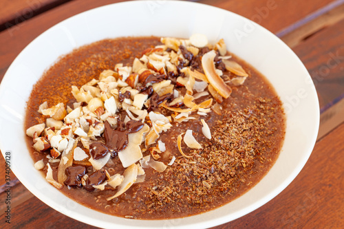 Breakfast bowl with quinoa, banana, coconut, cocoa, walnuts served on wooden table