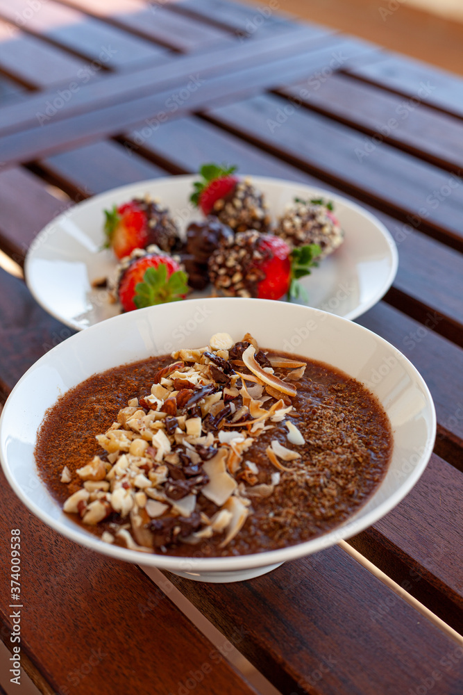 Breakfast bowl with quinoa, banana, coconut, cocoa, walnuts served on wooden table