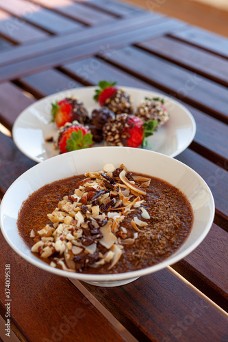 Breakfast bowl with quinoa, banana, coconut, cocoa, walnuts served on wooden table