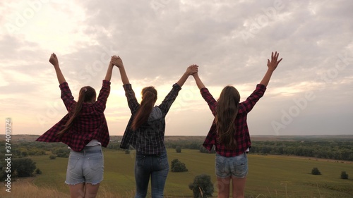 healthy girls, women go to top of the hill at sunset, raise their hands in the air, happy and intoxicated with life, youth and happiness. concept of freedom of adventure, tourism and travel