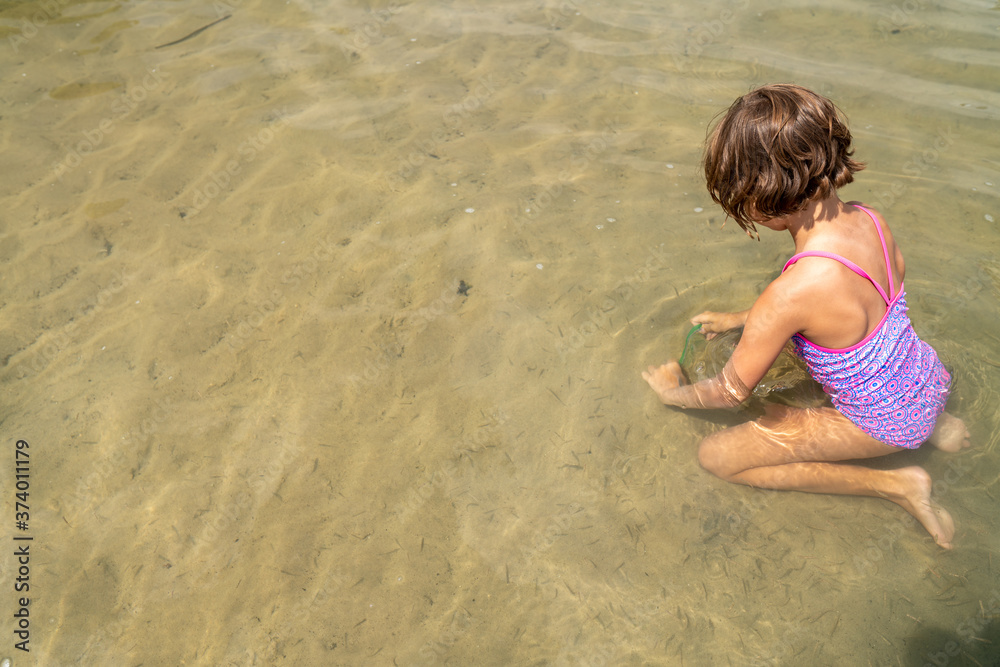 Young girl catching minnows in a lake during summer Young girl catching minnows in a lake during summer