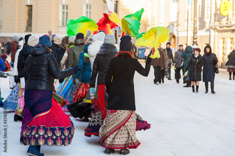 Naklejka premium Girls in winter jackets dance on a snowy street with fans. Hare Krishna sectarians