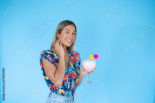 Blond woman with a drink on blue background smiling
