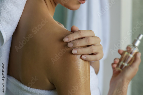 Woman applying body oil to moisturize her skin after shower, beauty skin care concept	