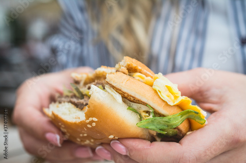 Tasty unhealthy burger sandwich in female hands