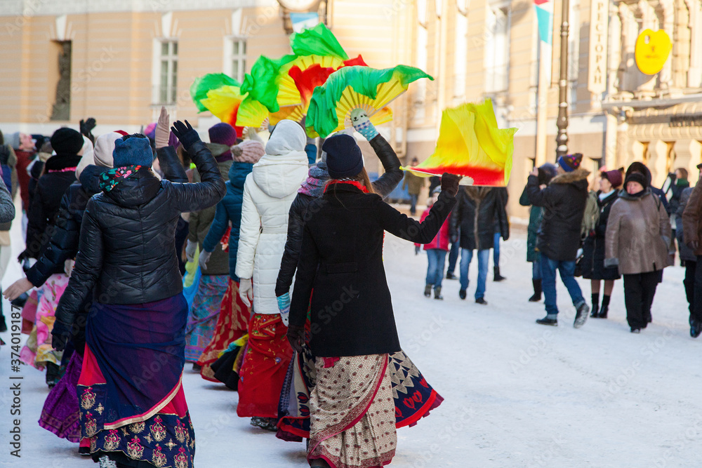 Naklejka premium Girls in winter jackets dance on a snowy street with fans. Hare Krishna sectarians