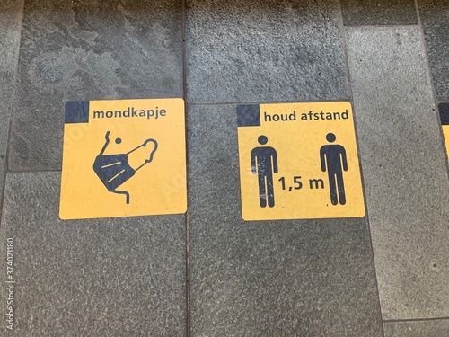 1,5 meter social distancing ( houd afstand) and mandatory face masks ( mondkapje) wearing signs at Eindhoven Centraal train station. Eindhoven, North Brabant / Netherlands. photo