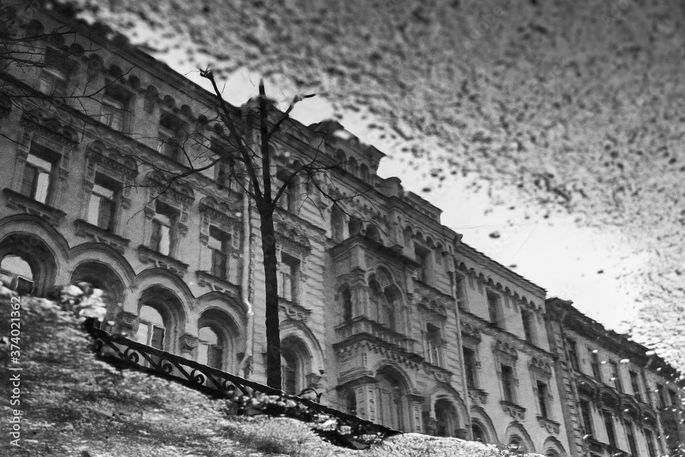 Facade of a vintage residential building reflected in a freezing puddle