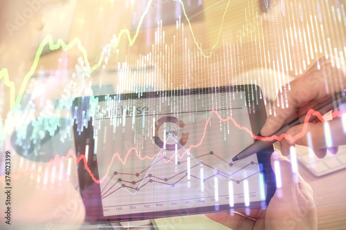 Double exposure of man's hands holding and using a phone and financial chart drawing. Market analysis concept.