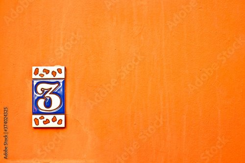 Small decorative number 3, three, offset in the corner on an orange background. photo